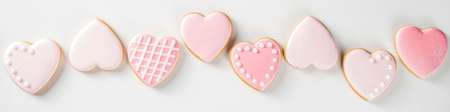 Homemade pick sugar glazed Valentine day cookies. Valentine heart shaped bakings. White stone background copy space top viewの写真素材