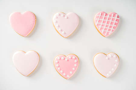 Homemade pick sugar glazed Valentine day cookies. Valentine heart shaped bakings. White stone background copy space top viewの写真素材