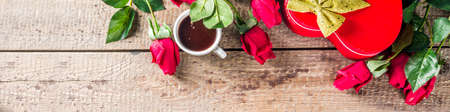 Valentine's day congratulations concept. Background for congratulation cards. Roses, valentine gift box with bow, cup of hot chocolate or coffee, notepad. On a wooden background, top view copy spaceの写真素材