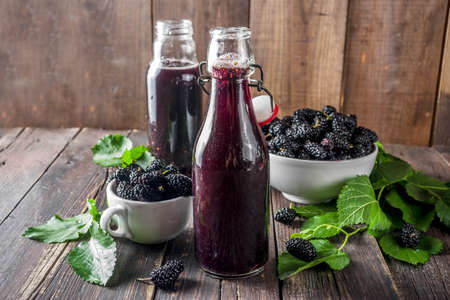 Mulberry Shrub, Juice or  liqueur in glass bottles, with fresh mulberries, rustic wooden background copy spaceの写真素材