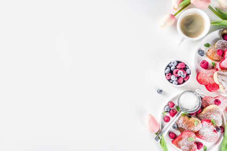 Valentine day brunch food recipe idea. Delicious homemade heart shaped red and white pancakes with berries. Concept of a festive breakfast for Valentine's Day, pleasant surprise for loved oneの写真素材