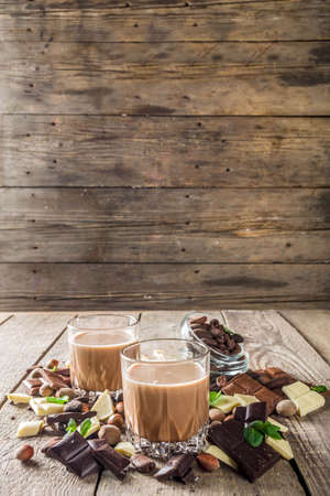 Sweet and strong alcohol drink. Chocolate liqueur with milk and dark chocolate pieces. Wooden background copy spaceの写真素材