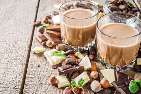 Sweet and strong alcohol drink. Chocolate liqueur with milk and dark chocolate pieces. Wooden background copy spaceの写真素材