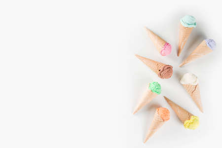 Colorful pastel ice cream with waffle cones, white background, copy space top view