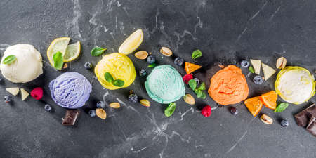 Colorful pastel ice cream with waffle cones and various flavor ingredients, black marble background, copy space top viewの写真素材