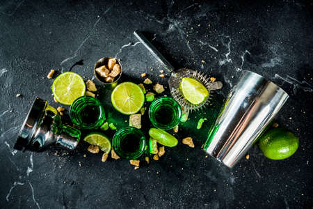 Strong alcohol. Absinthe with sugar, ice cubes and lime slices, Three shot glasses with absinthe....