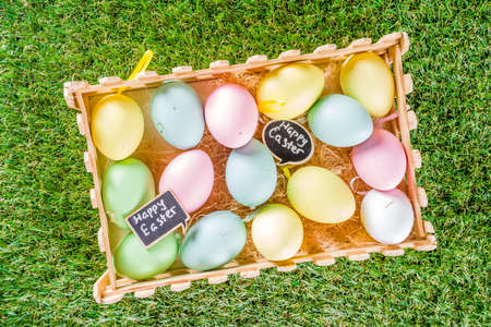 Colorful pastel Easter eggs on green and wooden garden terrace.  Funny spring decoration. Happy...
