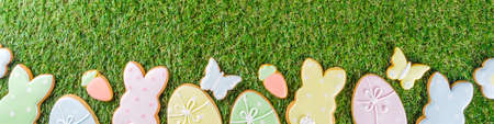 Sweet Easter baking cooking background with traditional Easter bunny and egg cookies, sugar sprinkles, Spring green grass background copy space layoutの写真素材