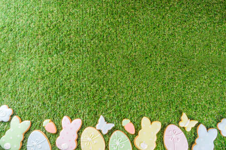 Sweet Easter baking cooking background with traditional Easter bunny and egg cookies, sugar sprinkles, Spring green grass background copy space layoutの写真素材
