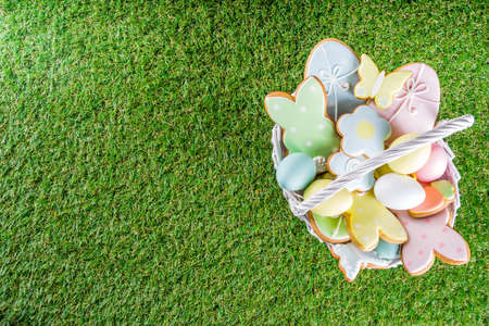 Sweet Easter baking cooking background with traditional Easter bunny and egg cookies, sugar sprinkles, Spring green grass background copy space layoutの写真素材