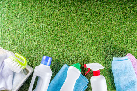 Spring home cleaning and housekeeping concept, Basket with cleaning items, utensils, supplies. Copy space over green background with spring blossom flowersの写真素材