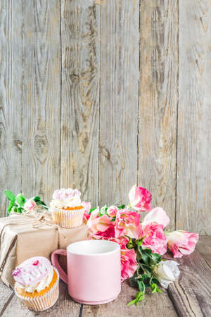 Happy moms day greeting background. Mothers day sweet cupcakes, with gift boxes, coffee cappuccino cup, flowers. Wooden background copy spaceの写真素材