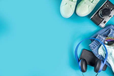 Stylish female spring autumn outfit and accessories on turquoise blue background, flat lay. Trendy girls clothes flatlay copy space top viewの写真素材