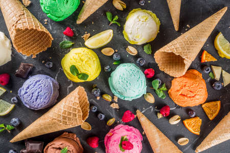 Colorful pastel ice cream with waffle cones and various flavor ingredients, black marble background, copy space top viewの写真素材