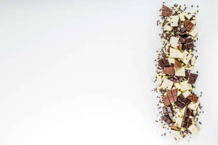 Assorted different types of chocolate. Broken pieces of dark, milk and white chocolate, with nuts, cooking chocolate, shavings. On a black stone concrete background, top view copy spaceの写真素材