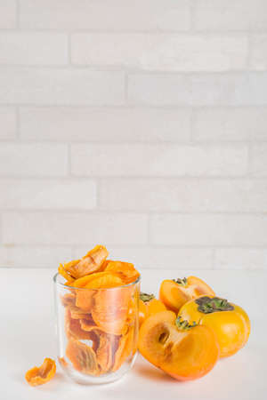 Dried persimmon fruit, with fresh persimmons, on white concrete or stone background copy spaceの写真素材