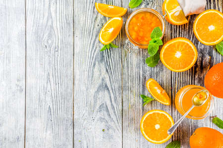 Homemade orange jam, with fresh sliced oranges and mint leaves, white wooden background copy spaceの写真素材