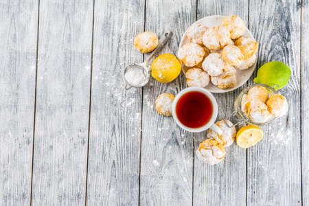 Lemon Crinkle Cookies, homemade sweet and sour baking with tea cup, white wooden background copy spaceの写真素材