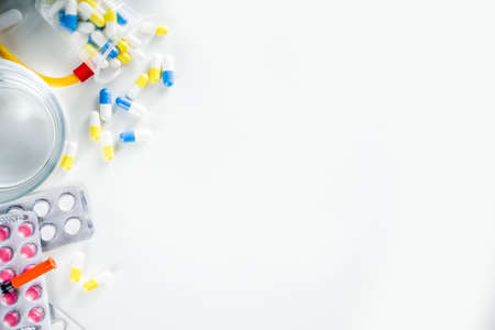 Pharmaceutical medicine pills concept, Assorted various pills, tablets and capsules with medical syringes, thermometer and water glass, copy space mockup, flatlayの写真素材