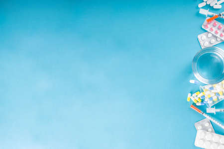 Pharmaceutical medicine pills concept, Assorted various pills, tablets and capsules with medical syringes, thermometer and water glass, copy space mockup, flatlayの写真素材