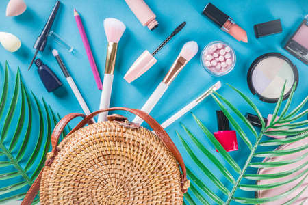 Professional makeup cosmetic set, with summer tropical leaves, woman bag. Make up items. luxury decorative cosmetics flatlay, top view, mockup. Beauty blogger concept. Trendy turquoise backgroundの写真素材