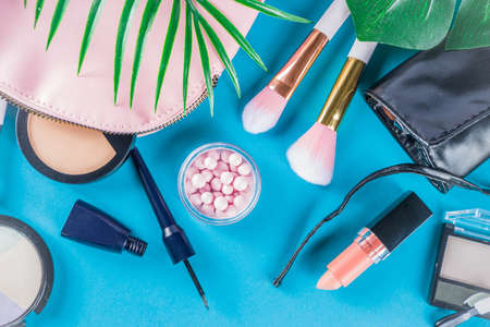 Professional makeup cosmetic set, with summer tropical leaves, woman bag. Make up items. luxury decorative cosmetics flatlay, top view, mockup. Beauty blogger concept. Trendy turquoise backgroundの写真素材