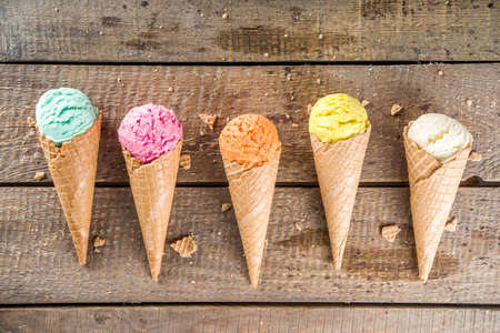 Set of various homemade colorful ice cream with icecream waffle cones on wooden background, copy...