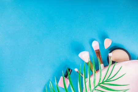 Professional makeup cosmetic set, with summer tropical leaves, woman bag. Make up items. luxury decorative cosmetics flatlay, top view, mockup. Beauty blogger concept. Trendy turquoise backgroundの写真素材