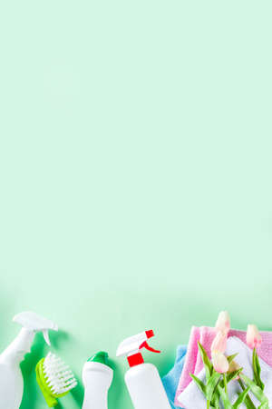 Spring home cleaning and housekeeping concept, Basket with cleaning items, utensils, supplies. Copy space over green background with spring blossom flowersの写真素材