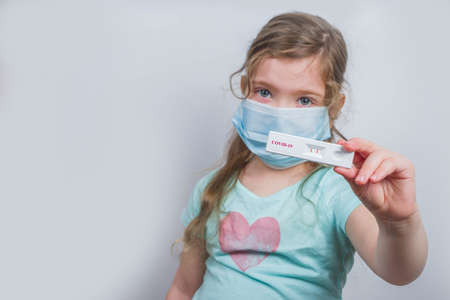 Worldwide coronavirus epidemic concept. Pandemic COVID-19, 2019-nCoV. Kid girl with positive test strip for antibody or sars-cov-2 virus disease in hands. White backgroundの写真素材