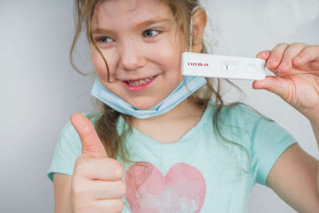 Worldwide coronavirus epidemic concept. Pandemic COVID-19, 2019-nCoV. Kid girl with negative test strip for sars-cov-2 virus disease in hands. After Coronavirus recovery conceptの写真素材