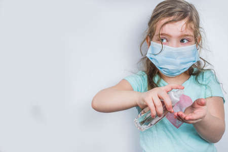 Worldwide coronavirus epidemic concept. Pandemic COVID-19, 2019-nCoV. Child kid girl in medical mask wash hands with alcohol antiseptic.の写真素材