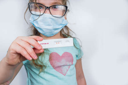 Worldwide coronavirus epidemic concept. Pandemic COVID-19, 2019-nCoV. Kid girl with positive test strip for antibody or sars-cov-2 virus disease in hands. White backgroundの写真素材