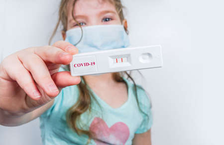 Worldwide coronavirus epidemic concept. Pandemic COVID-19, 2019-nCoV. Kid girl with positive test strip for antibody or sars-cov-2 virus disease in hands. White backgroundの写真素材