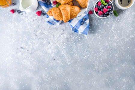 Sweet breakfast butter croissants with coffee cup, orange jam and fresh summer berries. Traditional continental breakfast with croissants concept, grey stone background copy spaceの写真素材
