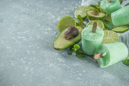 Homemade avocado ice cream. Vegan non-dairy ice cream. Avocado,lime and coconut healthy ice cream on grey stone background with fresh lime slices, avocados and iceの写真素材