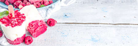 Sweet and tasty diet summer dessert. Homemade raspberry yogurt ice cream with fresh raspberries and mint. Healthy ice cream recipe. Wooden white background copy spaceの写真素材