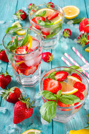 Strawberries and basil lemonade. Summer cold iced cocktail recipe, with fresh strawberry, lemon and basil leaves, wooden background copy spaceの写真素材