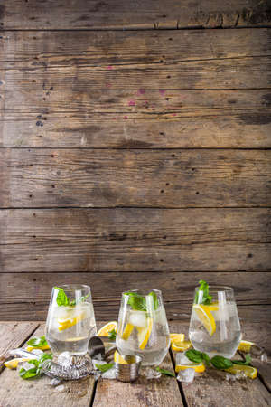 Boozy lemon basil lemonade, with fresh basil leaves, lemons and crushed ice, rustic wooden background copy spaceの写真素材