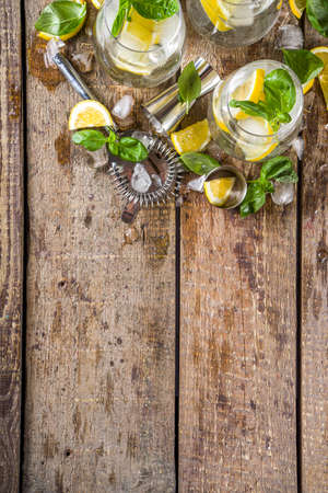 Boozy lemon basil lemonade, with fresh basil leaves, lemons and crushed ice, rustic wooden background copy spaceの写真素材