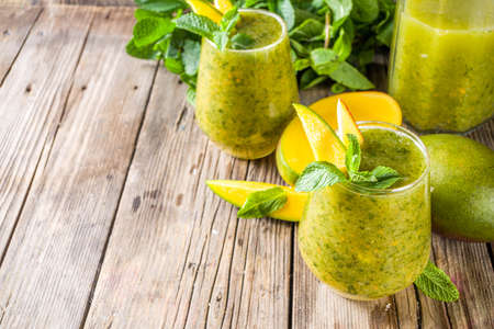 Summer unusual refreshing drink. Indian traditional salted lemonade aam panna (aam panha) cocktail, with mint and green mango. Indian mango mojito. On a wooden background with mango and mintの写真素材