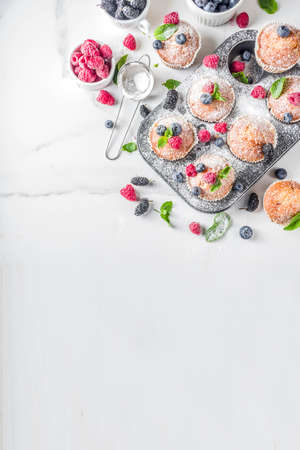 Homemade vanilla muffins or cupcakes with fresh berries on  white marble backgroundの写真素材