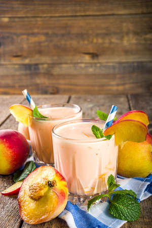 Summer breakfast drink, fresh blended peach smoothie, peach yogurt with nectarine fruit slices, rustic wooden background copy spaceの写真素材