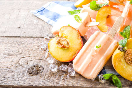 Homemade peach ice creams, fruity lollipop non-dairy vegan gelato, on grey old wooden backgroundの写真素材