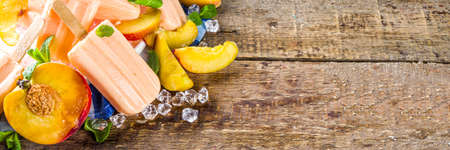 Homemade peach ice creams, fruity lollipop non-dairy vegan gelato, on grey old wooden backgroundの写真素材