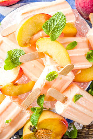Homemade peach ice creams, fruity lollipop non-dairy vegan gelato, on grey old wooden backgroundの写真素材