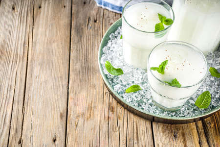 Cold Indian drink Lassi, iced coconut Lassi drink with mint leaf, wooden background copy space