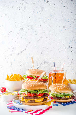 Celebrating Independence Day, July 4. Traditional American Memorial Day Patriotic Picnic with burgers, french fries and snacks, Summer USA picnic and bbq concept, White concrete backgroundの写真素材