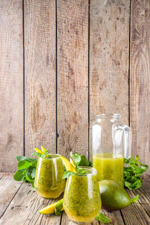 Summer unusual refreshing drink. Indian traditional salted lemonade aam panna (aam panha) cocktail, with mint and green mango. Indian mango mojito. On a wooden background with mango and mintの写真素材