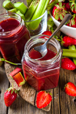 Homemade strawberry rhubarb jam or sauce, with fresh rhubarb and strawberries and spices, wooden rustic background copy space の写真素材